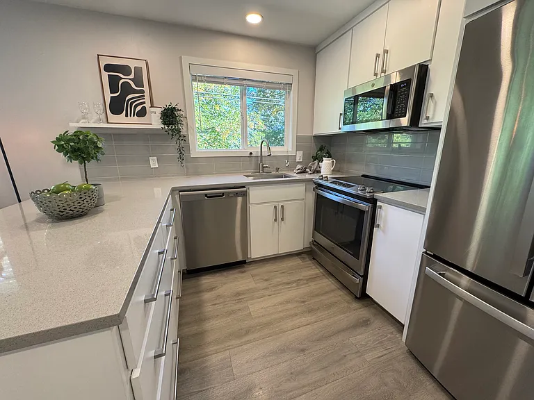 Bright U-shaped kitchen with large window, modern backsplash, and ample storage.