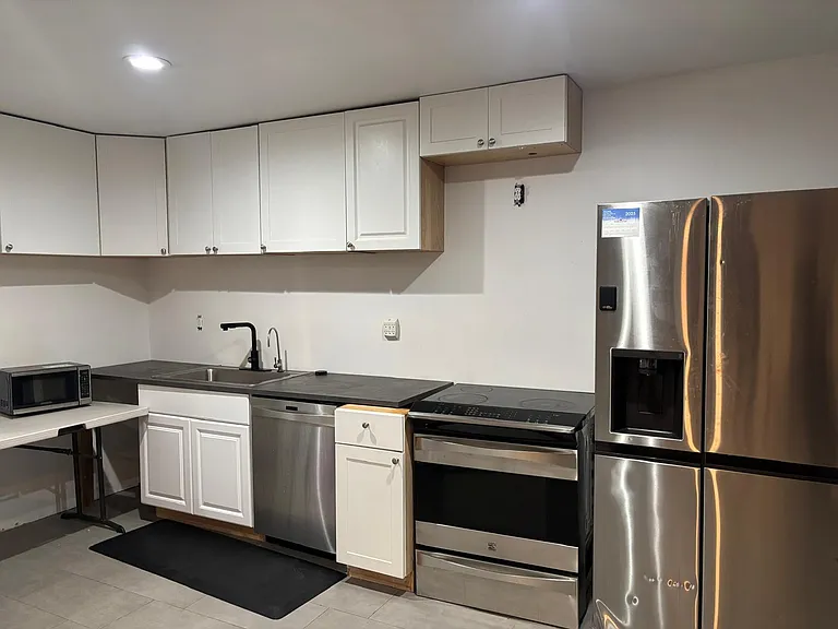 Efficient kitchen with ample upper cabinetry, generous counter space, and stainless steel refrigerator and range.