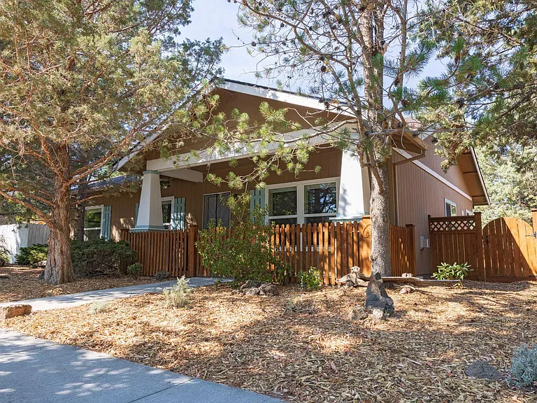 Front of the house with xeriscaped yard, enclosed gate around front porch, and gate leading to enclosed back yard