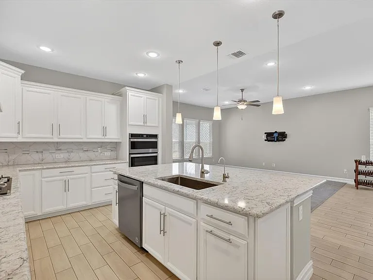 Kitchen featuring white cabinetry, light-toned countertops, a center island with sink, stainless steel appliances, and recessed lighting