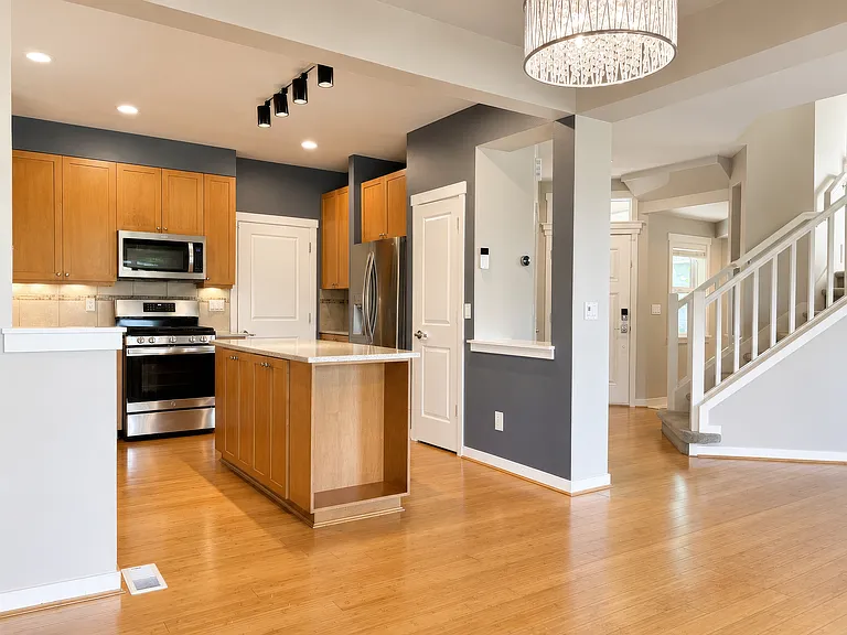 View of kitchen, front door, and stairs from the dining area