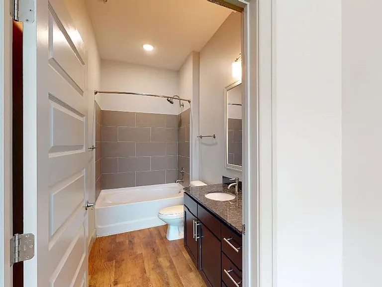 Apartment bathroom with large soaking tub and wood-style flooring.