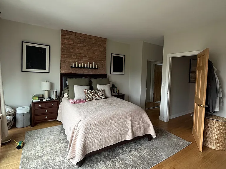 Primary bedroom with exposed brick wall.