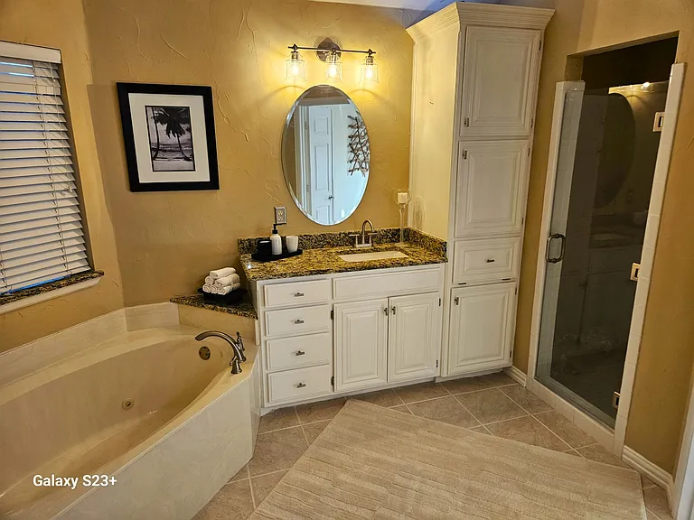 Master bath with separate dual vanities, walk-in shower, and separate tub