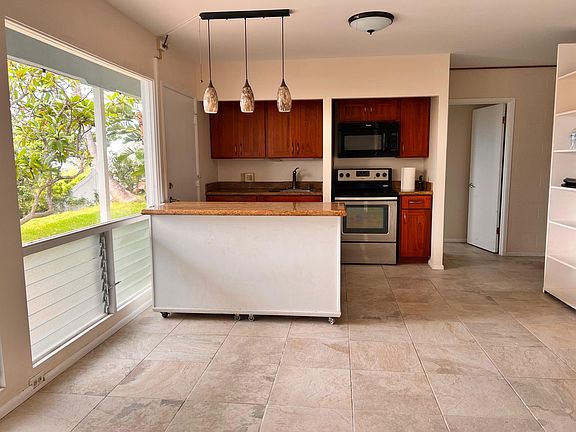 Open living room area and adjacent kitchen island, sink, stove and microwave.