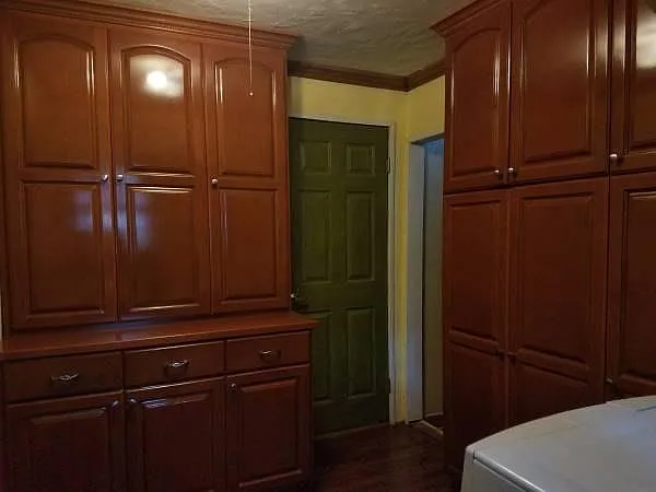 beautiful natural wood laundry room cabinetry (green door leads to primary bedroom)