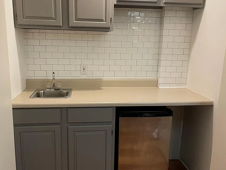 Basement wet bar with sink and small fridge