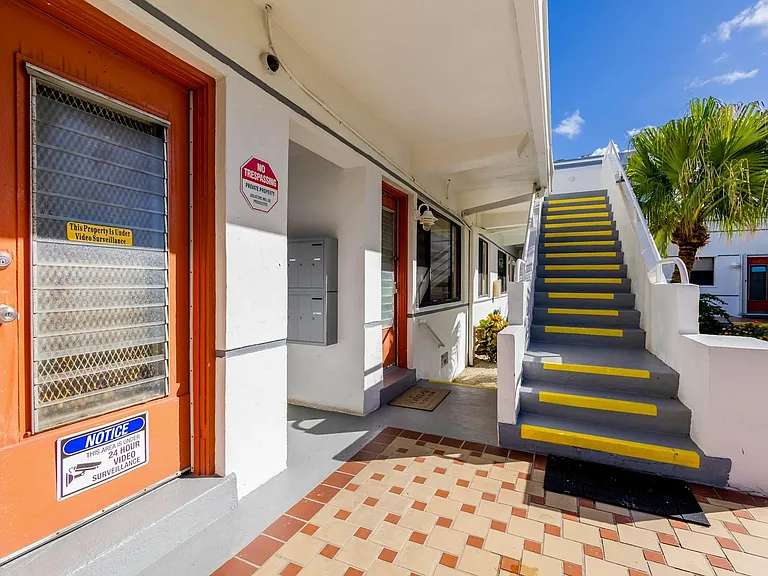 Covered exterior entry with tiled walkway, stair access to upper level, and convenient on-site mailboxes.
