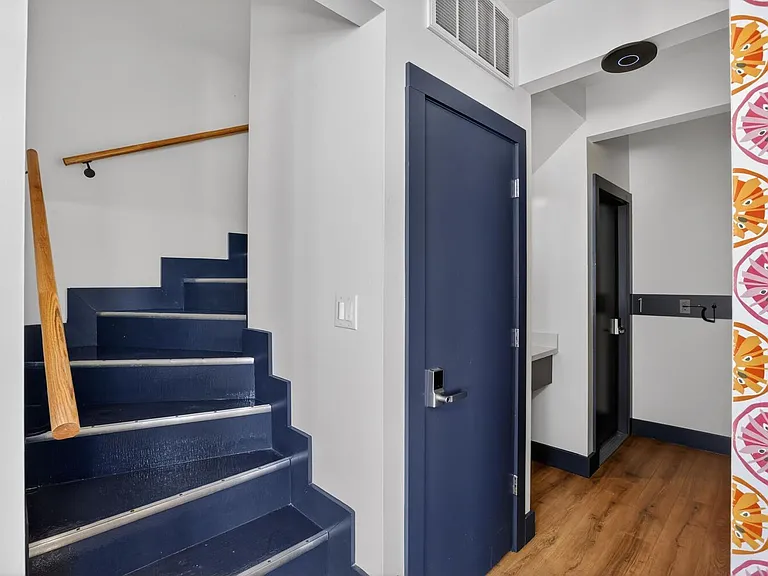 Clean entry hallway with wood-look flooring, stair access, and a built-in coat hook rail for everyday convenience.