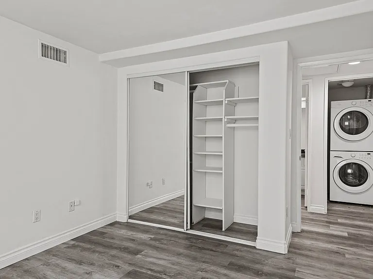 Bedroom with Closet with Shelving and an In-Suite Washer & Dryer Unit in the Hallway