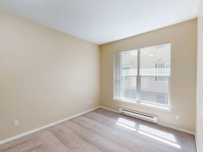 Spacious apartment bedroom with plush carpet flooring.