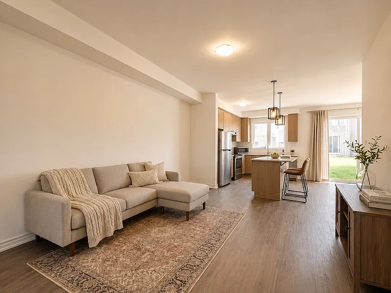 Bright & inviting open-concept great room with warm natural tones, oversized windows, and a modern kitchen featuring granite countertops, stainless steel appliances, and a spacious island perfect for entertaining.