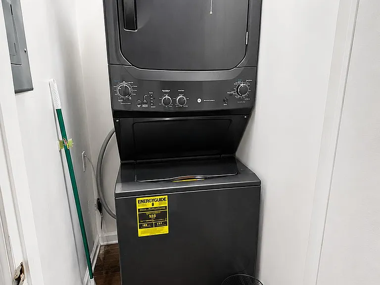 Dedicated laundry nook with stacked washer/dryer and easy-access controls, set on durable wood-look flooring.