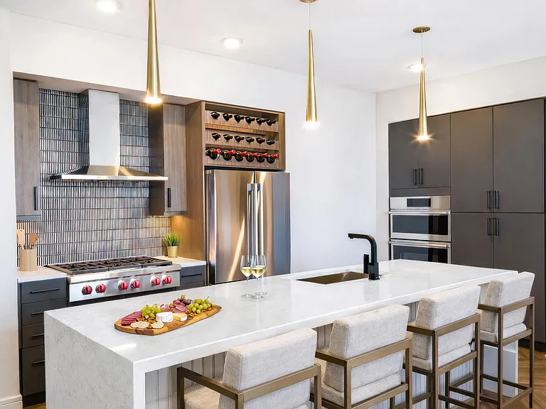 This penthouse kitchen features an expansive island, built-in wine storage, and design-forward finishes throughout.