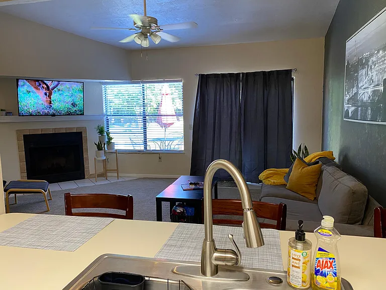Kitchen overlooking large social room with view to deck and community pool