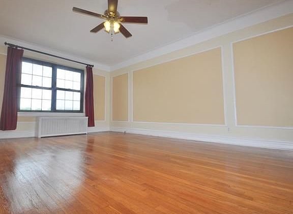 Large Sunny living room with a cove ceiling, wall and picture molding and refinished hardwood floors