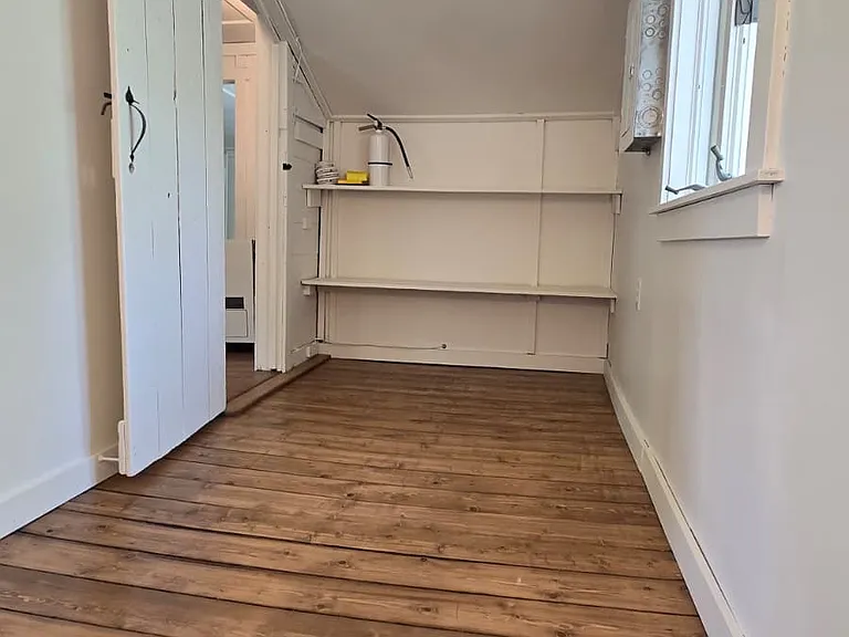 A third bedroom with built-in open shelving and east- and west-facing windows.