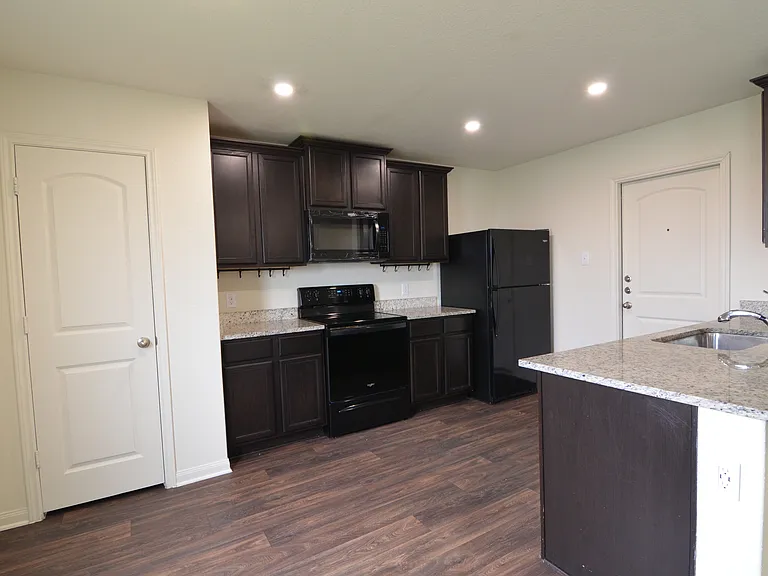 Modern kitchen featuring granite countertops, dark cabinetry, breakfast bar, and full appliance package.