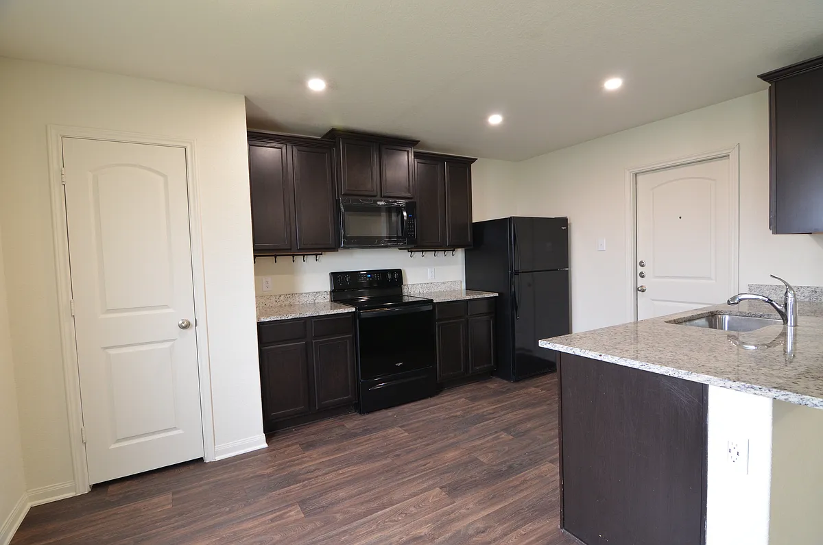 Modern kitchen featuring granite countertops, dark cabinetry, breakfast bar, and full appliance package. - 233 Wincliff Ln
