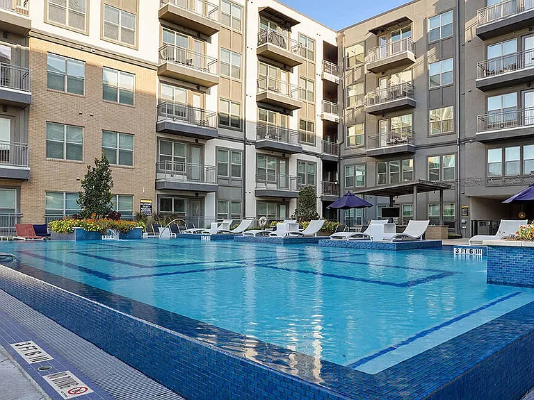 Resort-style pool with lounge chairs and gazebos.