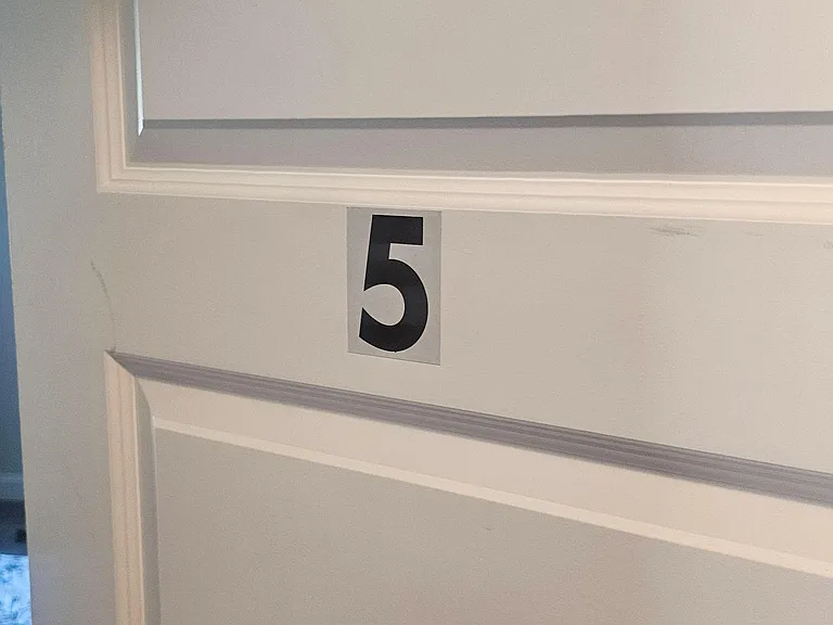Interior door with decorative trim and a labeled room number, providing clear wayfinding within the home.