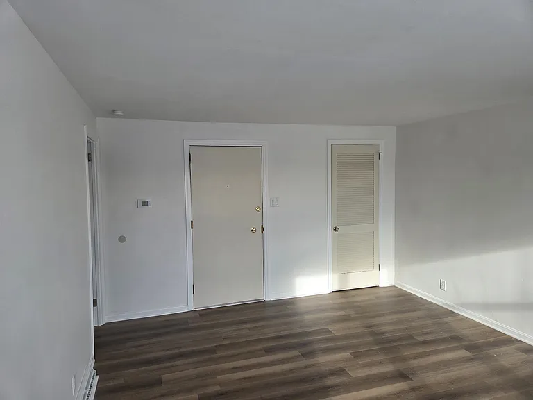 Looking at the front door and main room closet from inside the living room.