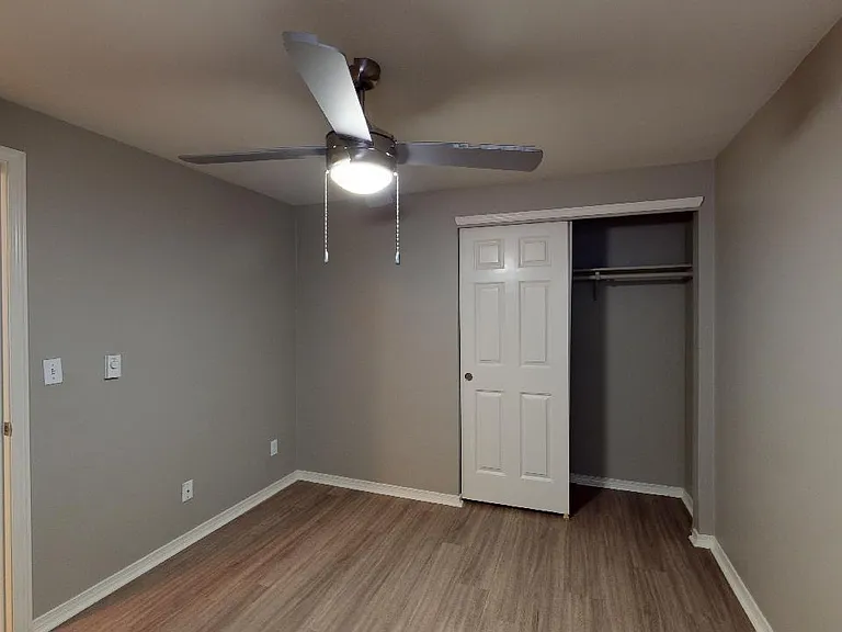 Spacious apartment bedroom with wood-style flooring.