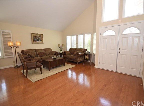 Large living room with high vaulted ceilings, wood floors, plantation shutters, dual pane windows and chandelier. bright and airy.