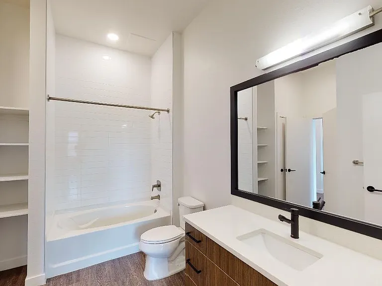 Apartment bathroom with large soaking tub and wood-style flooring.