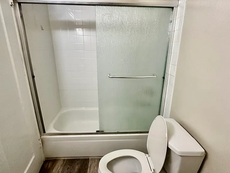 Full sized bathroom with bathtub, and real glass shower doors.