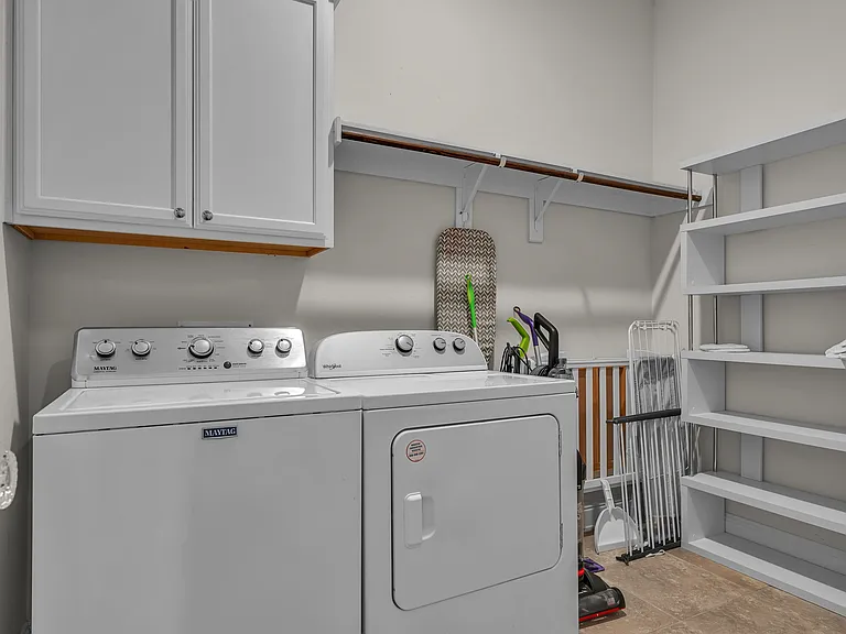 Large laundry center with a baby bed if needed, iron, ironing board, cleaning supplies, and shelving