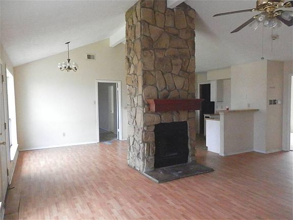 Stone facade, wood-burning fireplace acts as a room divider between living and eating areas.