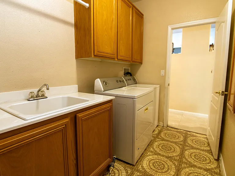 Convenient laundry area with utility sink, upper storage cabinets, and in-home washer/dryer for easy everyday routines.