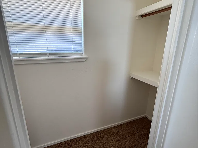 walk in closet entry (with door and window) upper and lower hanging clothes area.