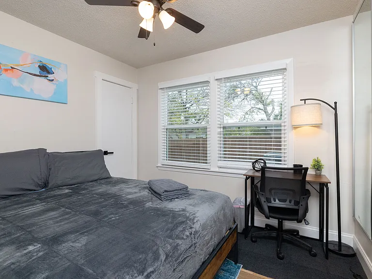 Bedroom 4 features a bright dedicated workspace with a sleek desk, ergonomic chair, and warm lighting by large windows_ideal for remote work, studying, or quiet focus during your stay.