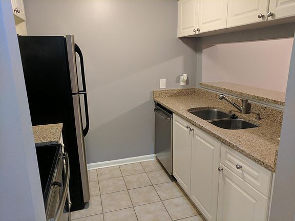 Kitchen with double sided stainless steel under counter sinks, Dishwasher, Range and Refrigerator, Granite countertops. Ceramic tile floor.
