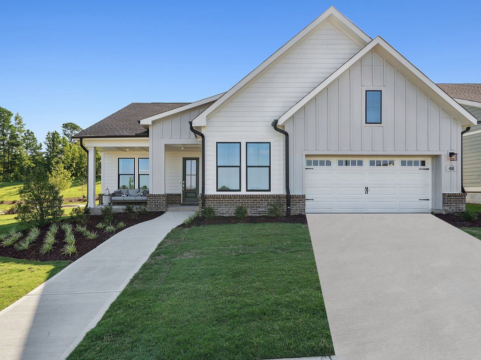 A modern, two-story house with a white exterior, a gabled roof, and a well-manicured lawn in the for