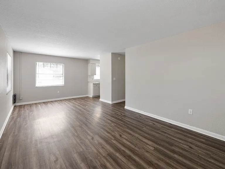 Spacious open-concept living area with natural light and sleek hardwood floors, perfect for modern living.