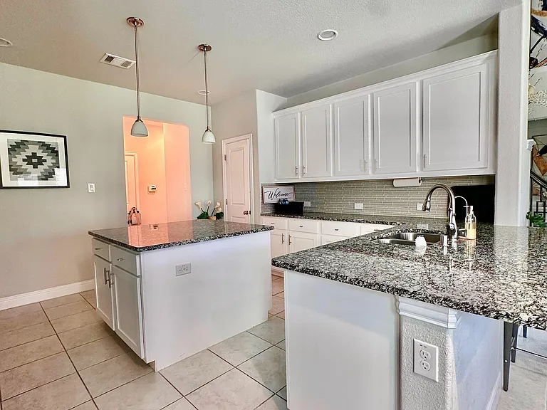 Spacious kitchen with granite counters, a large island, ample cabinetry, and a deep sinkideal for cooking and meal prep.