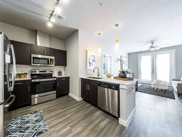 Kitchen overlooking living room with track ceiling lighting and modern light fixtures over kitchen island