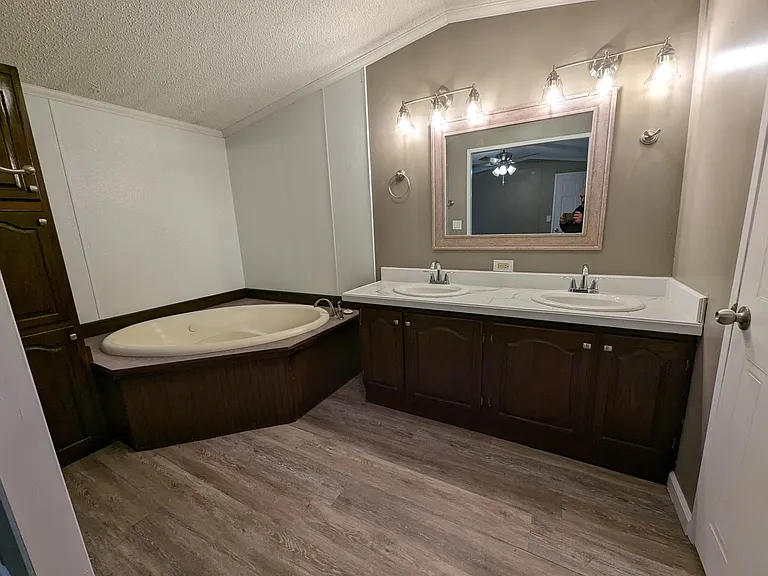 ensuite master bath with double vanity, lots of lighting and a jacuzzi tub and a large linen cabinet