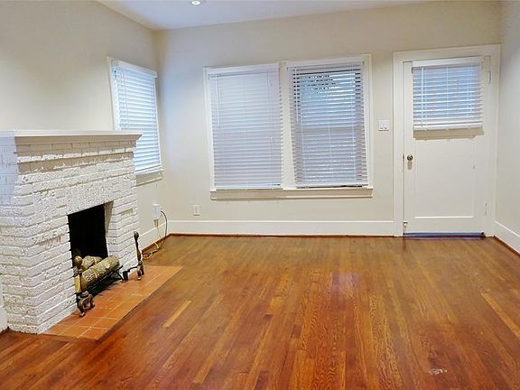 Spacious living room with central fireplace, recessed lighting and original hardwood flooring