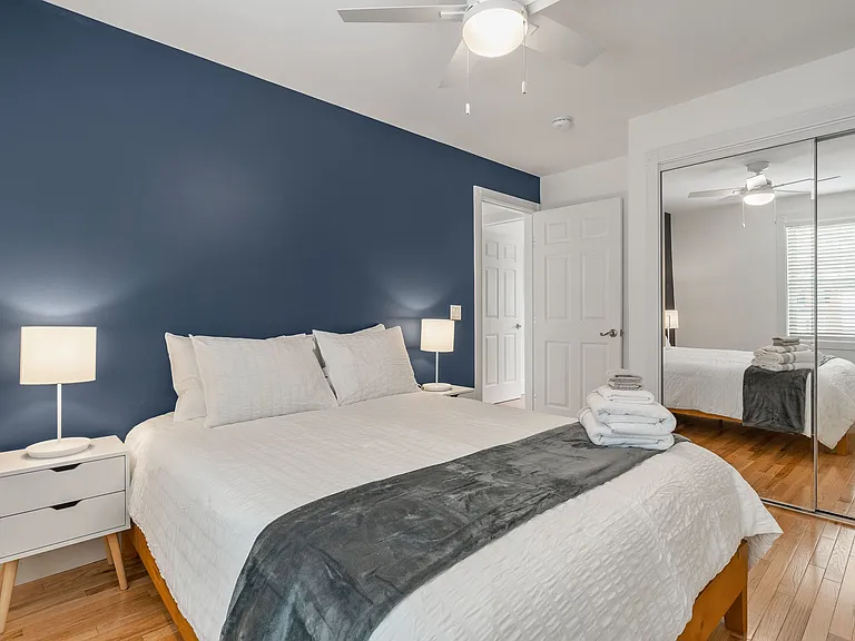 Primary Bedroom, Accent Wall, Hardwood Floors, Natural Light, Mirrored Closets, Ceiling Fan, Modern Lighting.