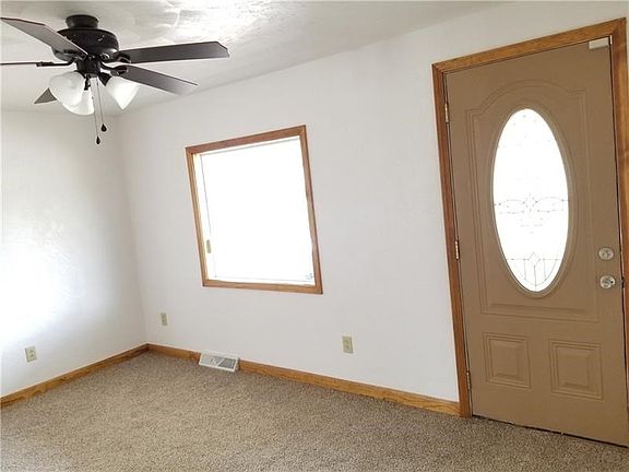 Bright sunlit living room with new ceiling fan/light fixture and wall-to-wall carpeting.