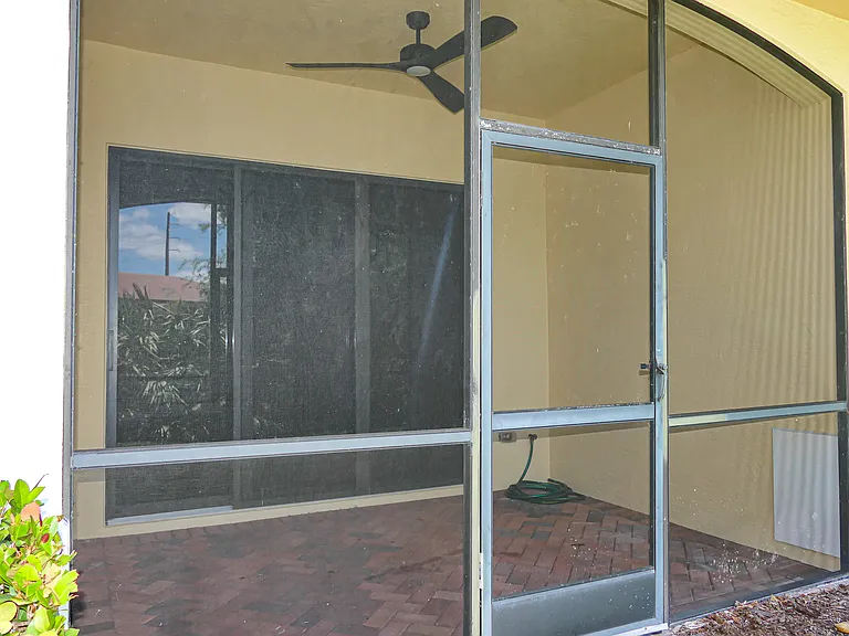 Rear view of screened in patio. Paver floor. Hose bibb and ceiling fan in view