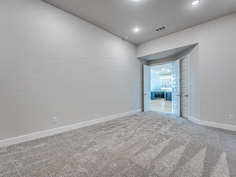 Spacious room featuring neutral carpeting, light gray wall paint, and white baseboards