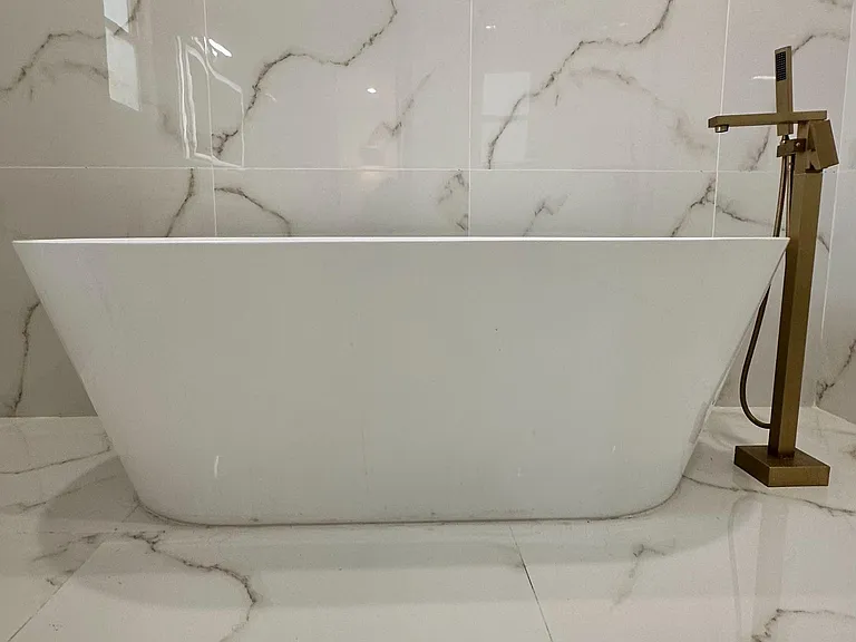 Spa-style bathroom features a freestanding soaking tub with floor-mounted faucet, paired with large-format marble-look tile.
