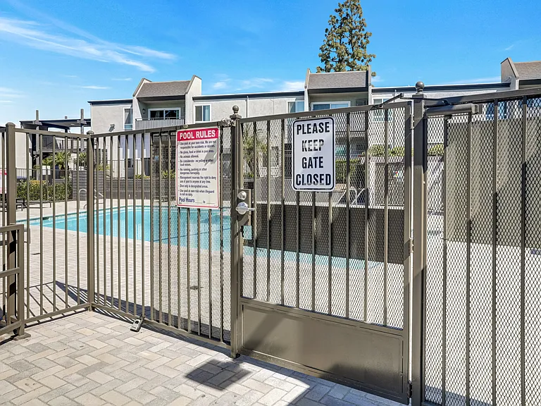 A pool area is gated off with a sign that says Please keep gate closed