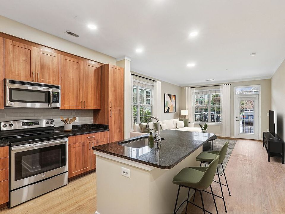 Renovated Package I kitchen with stainless steel appliances, oak cabinetry, grey tile backsplash, black granite countertops, and updated hard surface flooring and lighting