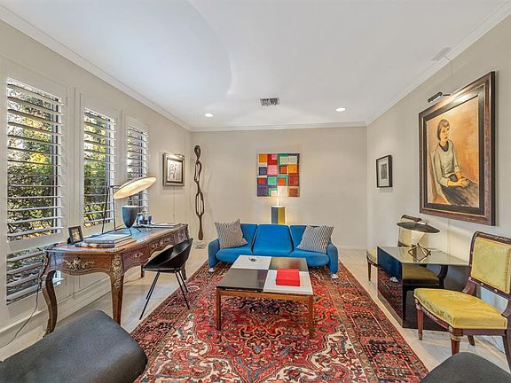 The formal living room features crown moulding and plantation shutters. This room can be used a study.